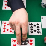 Рука гравця над картами й фішками на зеленому столі для блекджеку